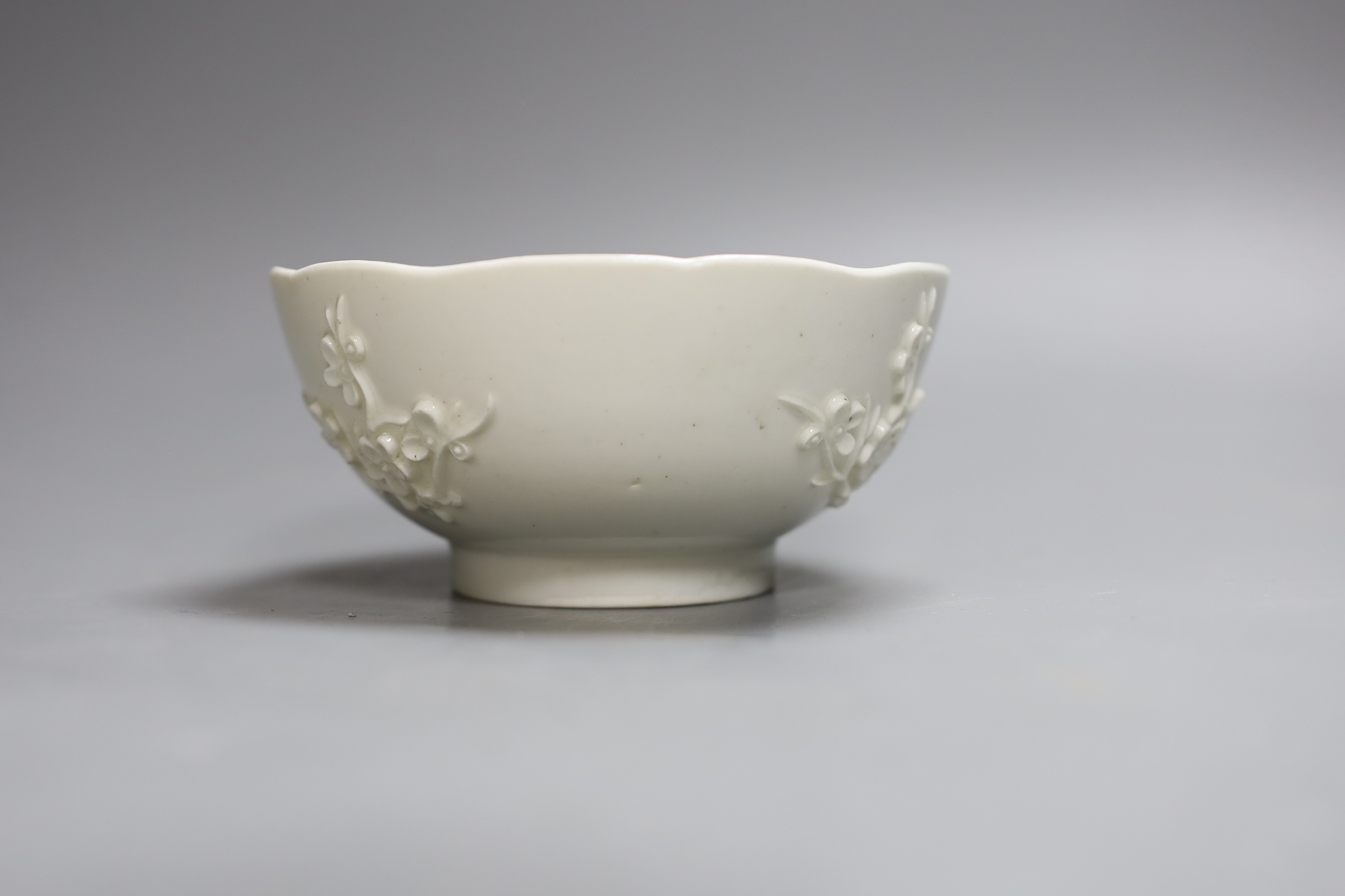 An 18th century Bow white glazed ‘prunus’ bowl, and a Bow octagonal plate, with floral design, 21cm diameter